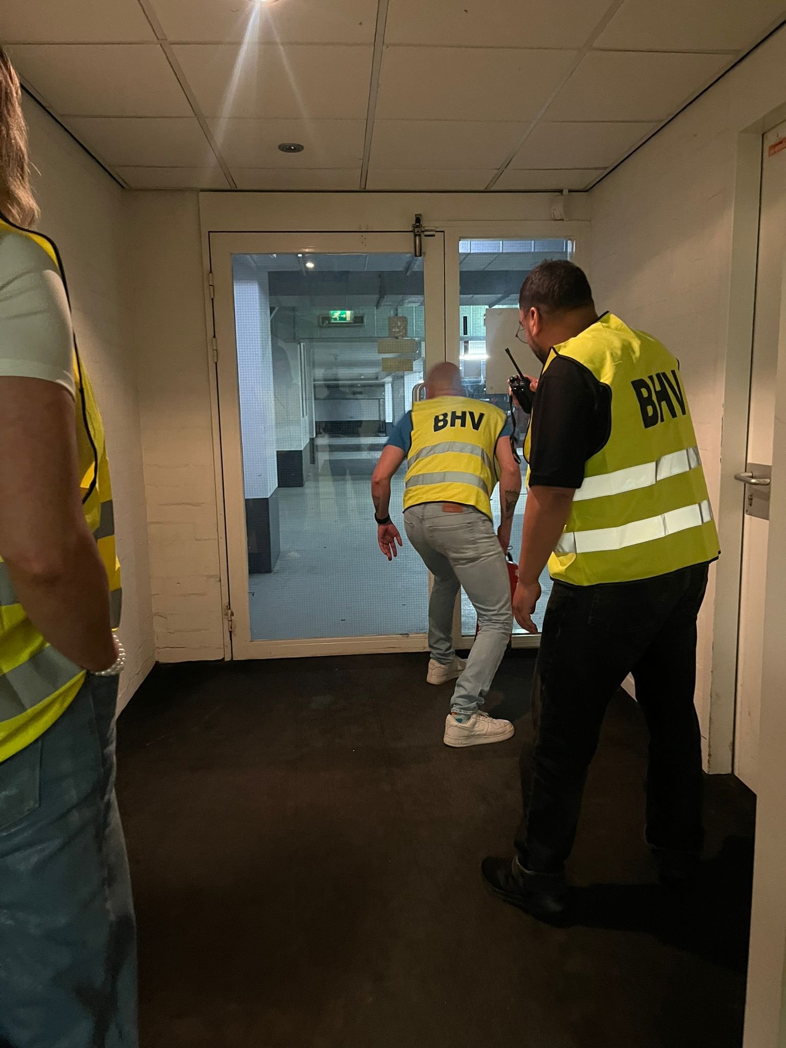 BHV’ers oefenen bij een deur; een deelnemer communiceert via een portofoon